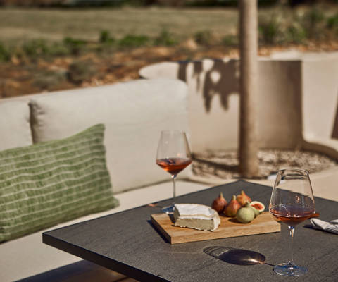 Zelia Resort Halkidiki Zest Pool Bar outdoor couch and a table with two glasses of wine and snacks
